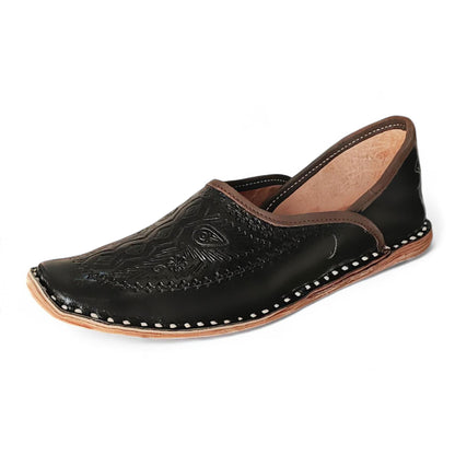 A single black leather Moroccan jodhpuri mojari slip-on shoe with hand-stitched detailing, decorative embossed patterns on the toe, and contrast stitching, shown against a plain white background.